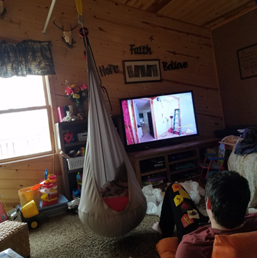 A swing is attached to a lift system and a boy sits inside the swing.