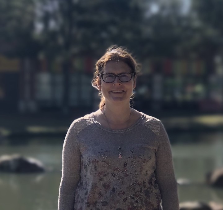 Jennifer stands smiling in front of a pond.