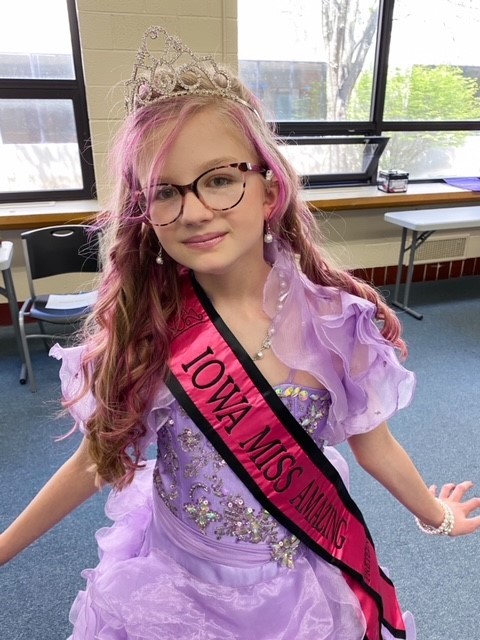 Lani wearing a purple dress and her Iowa Miss Amazing sash.