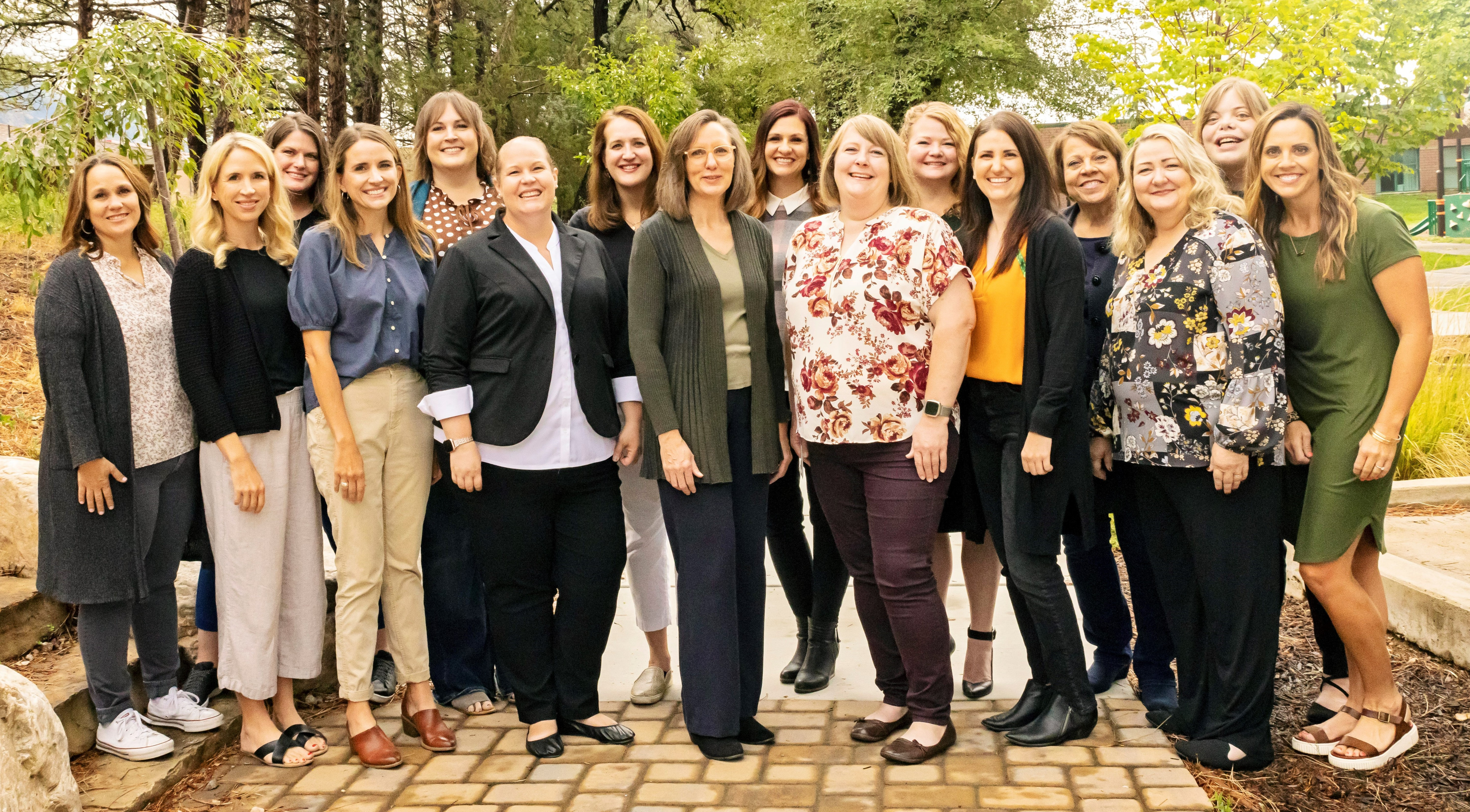 Sixteen staff members of Utah Schools for the Deaf and Blind standing outside smiling at camera.